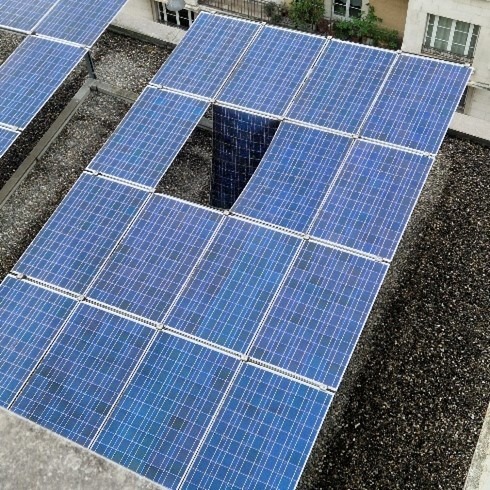 Toiture partiellement équipée de panneaux photovoltaïques – installation incomplète et à rénover. Vue plongeante sur un toit avec des panneaux solaires manquants et usés, montrant un système photovoltaïque incomplet et défectueux.